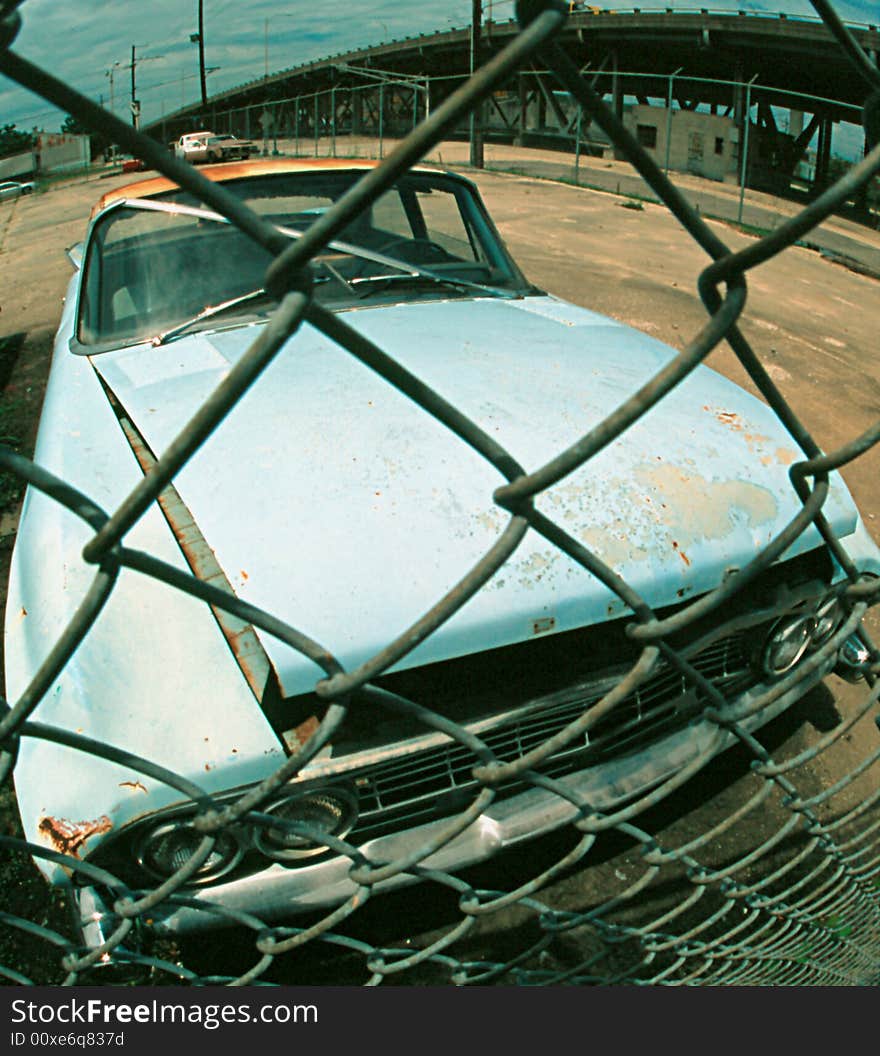 Rusted car behind metal fence transportation. Rusted car behind metal fence transportation