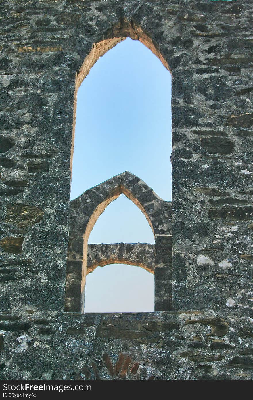 An old historic arched window with blue sky background