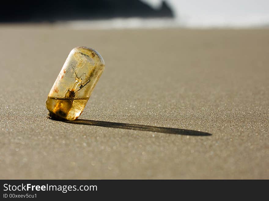 Old light bulb washed up on beach, half filled with water, environmental concept, shallow depth of field. Old light bulb washed up on beach, half filled with water, environmental concept, shallow depth of field