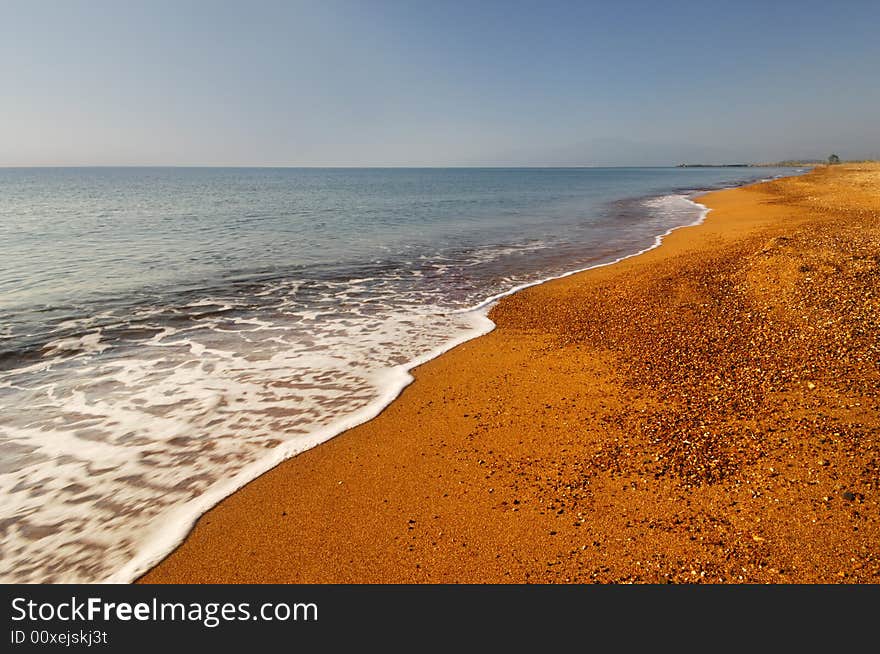 Image shows a long and inviting empty mediterranean beach with bright golden sand. Image shows a long and inviting empty mediterranean beach with bright golden sand.