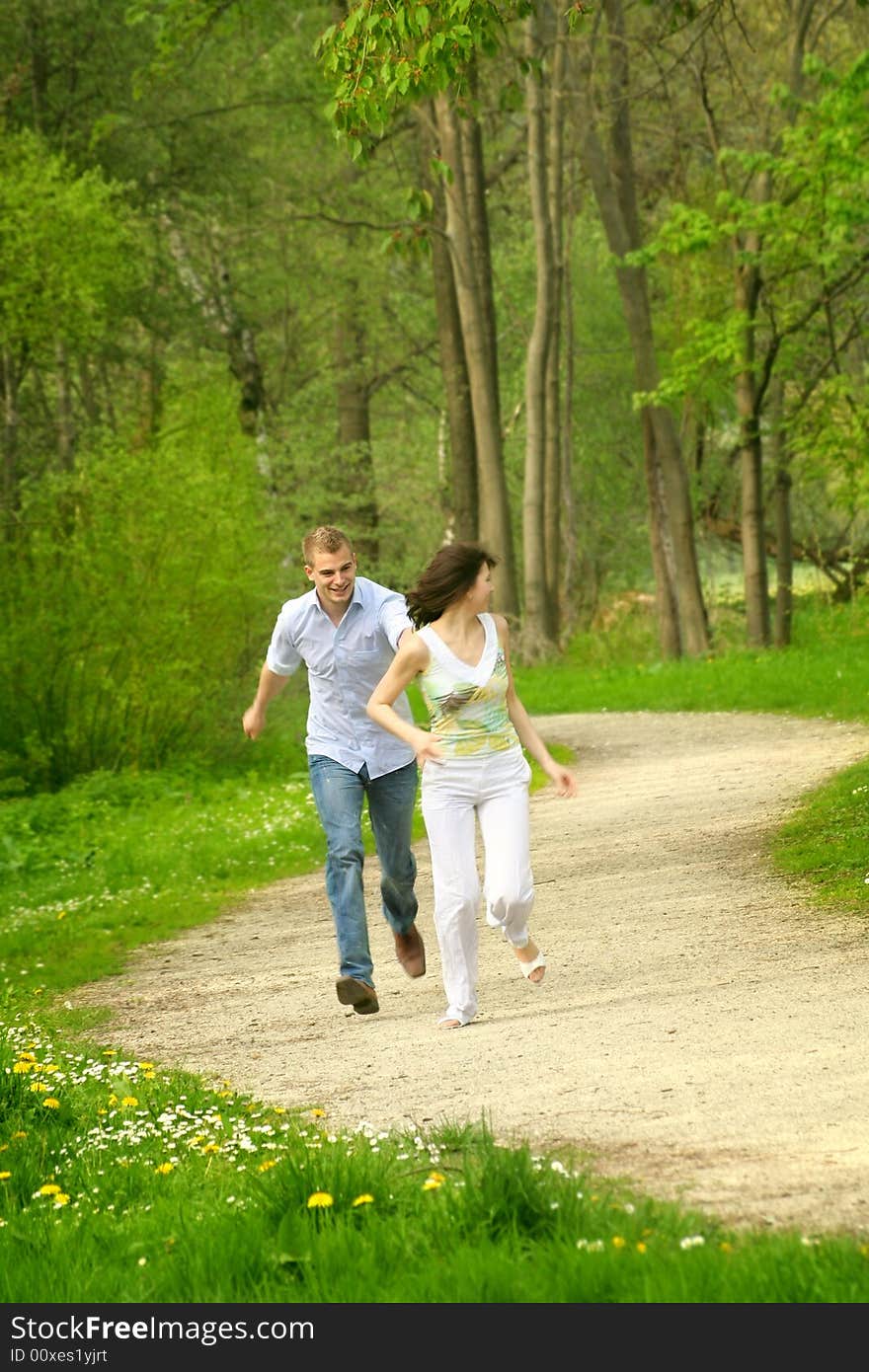 A young happy and smiling couple is playing tag. A young happy and smiling couple is playing tag