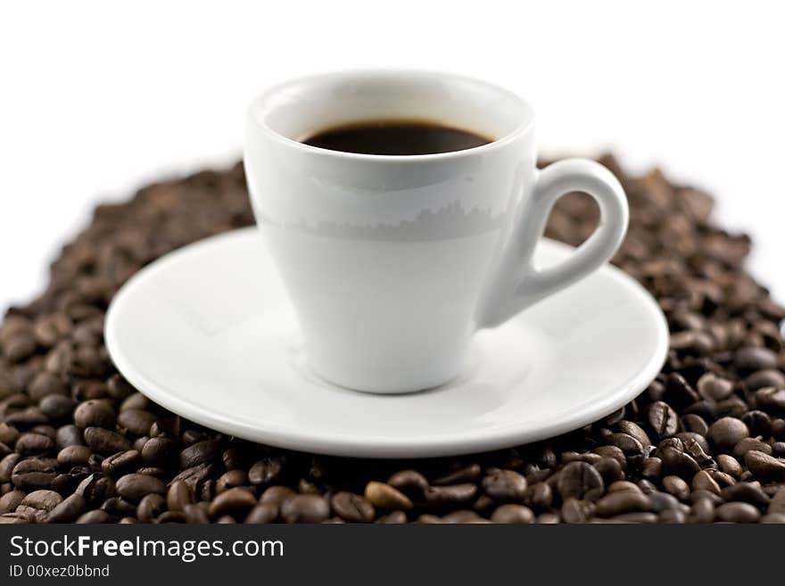 Classic white espresso cup on coffee beans