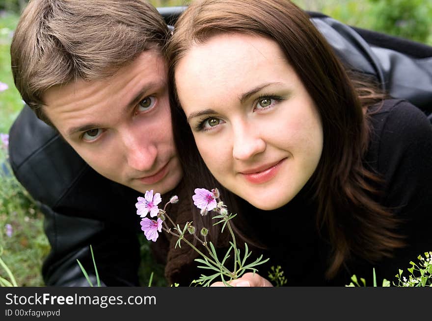 The guy and the girl with a flower lay on a grass. The guy and the girl with a flower lay on a grass