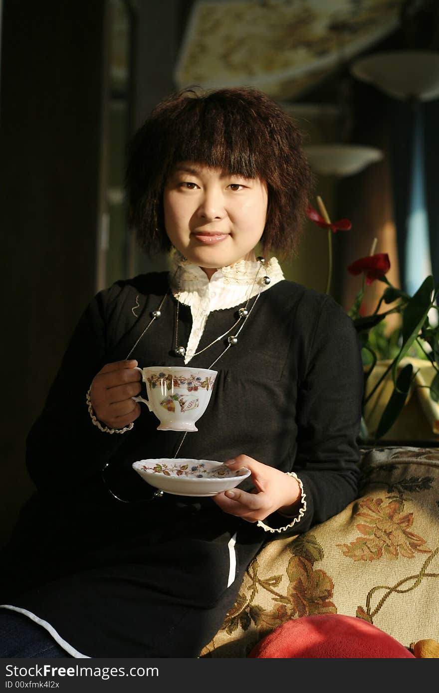 A beautiful young woman holding a cup of hot drink