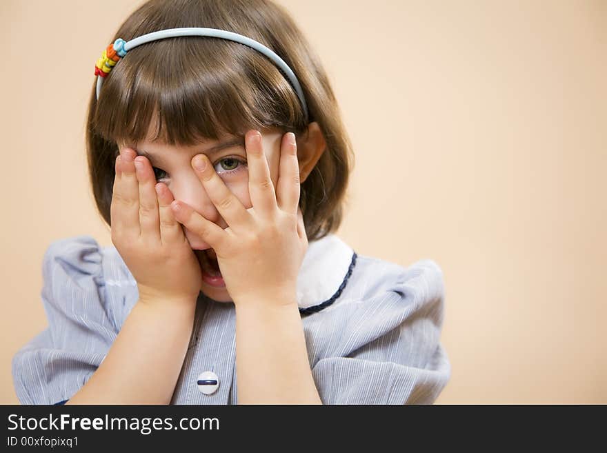 Little girl gazing through her fingers, astonished. Little girl gazing through her fingers, astonished