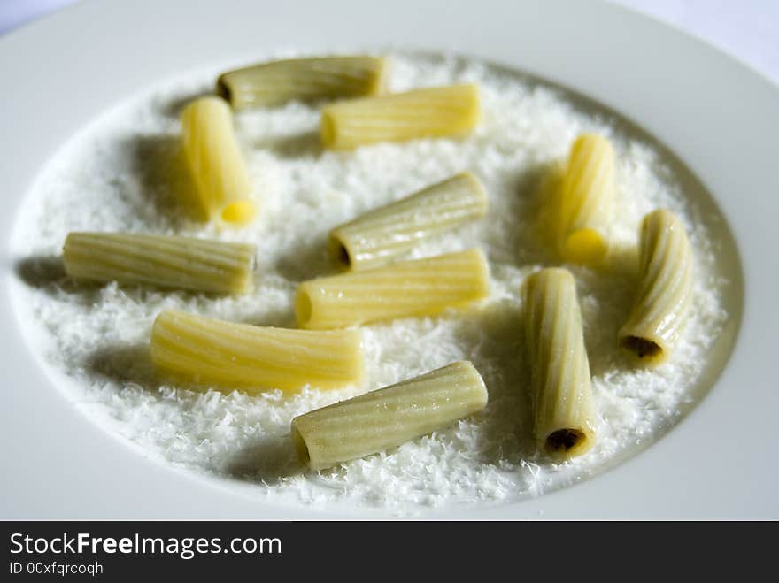 A plate of cooked pasta lighted from the right side to create shadows on the left. A plate of cooked pasta lighted from the right side to create shadows on the left.