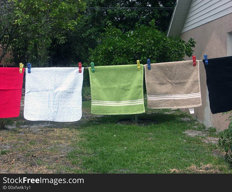 A line of colorful face cloths are hanging on a wash line. A line of colorful face cloths are hanging on a wash line