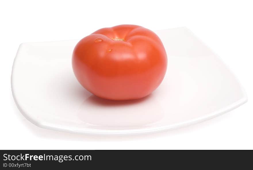 Red ripe tomato lying on a white square ceramic plate. Red ripe tomato lying on a white square ceramic plate