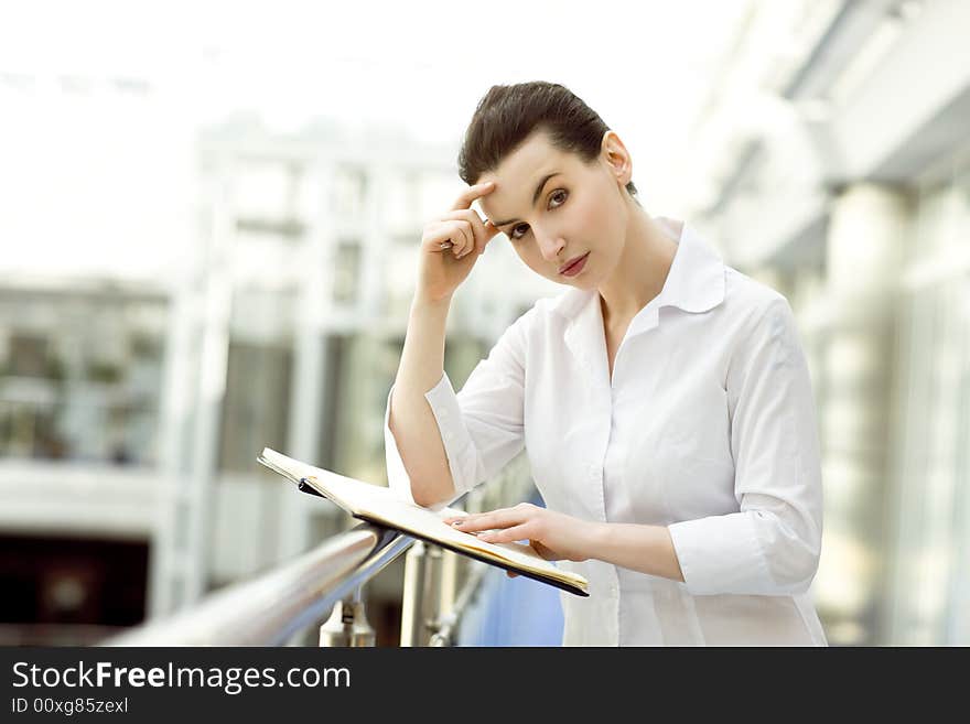 Portrait of young woman standing with business diary in modern office building. Portrait of young woman standing with business diary in modern office building