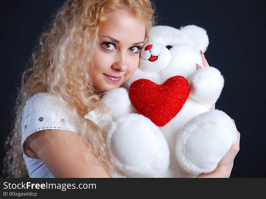 The beautiful girl with a toy in hands on a black background. The beautiful girl with a toy in hands on a black background