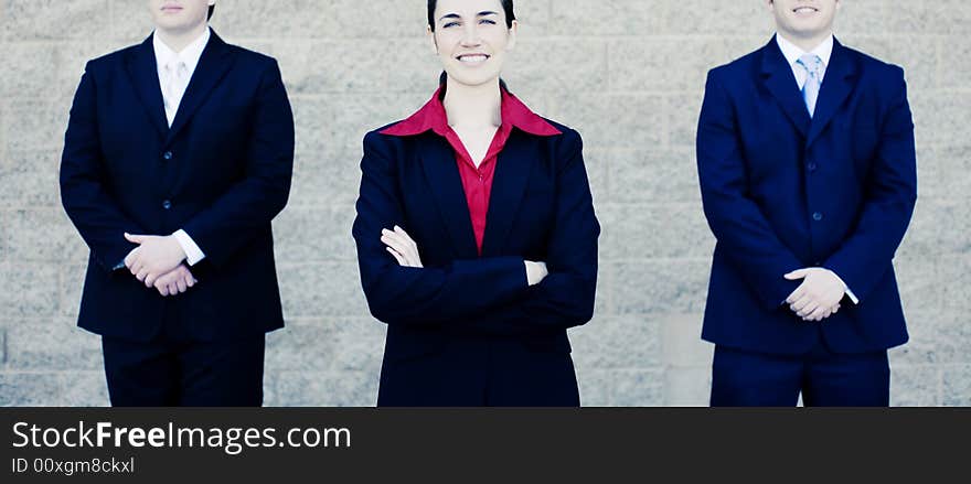 Attractive businesswoman stands between two businessmen in suits. Attractive businesswoman stands between two businessmen in suits