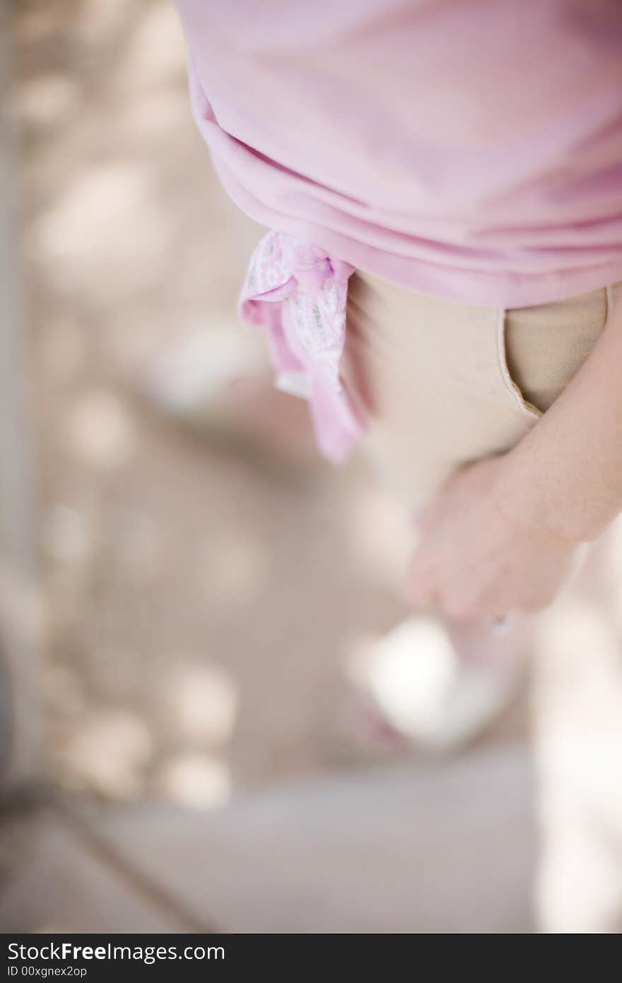 Woman standing outside in the summer with a pink bow on her shorts as she wears a pink shirt