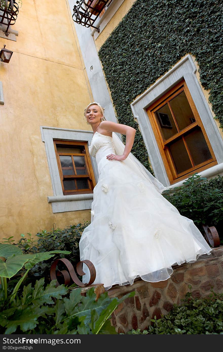 A bride standing in a courtyard in her dress. A bride standing in a courtyard in her dress