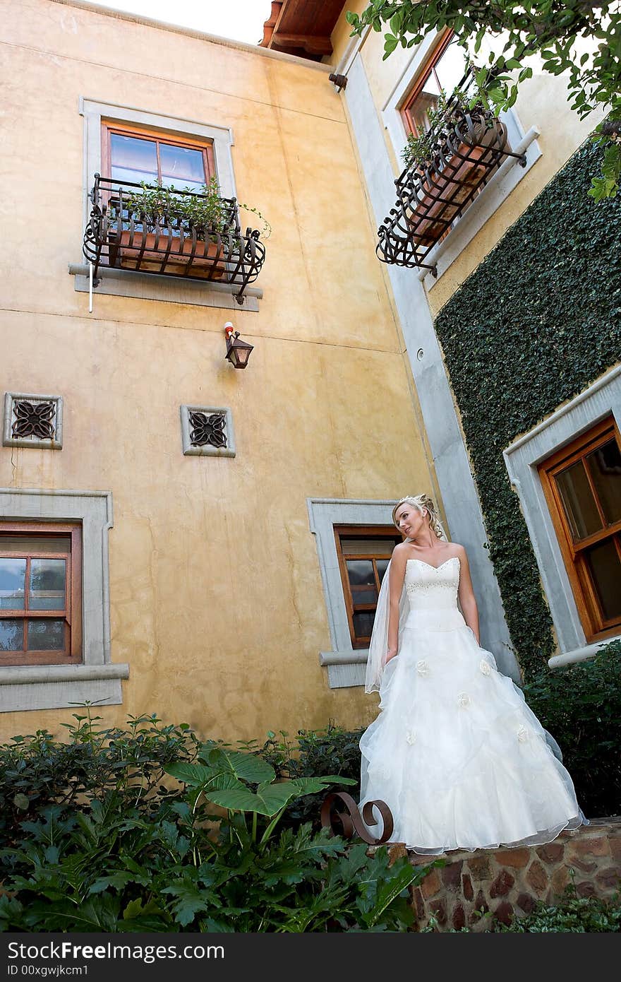 A bride standing in a courtyard in her dress. A bride standing in a courtyard in her dress