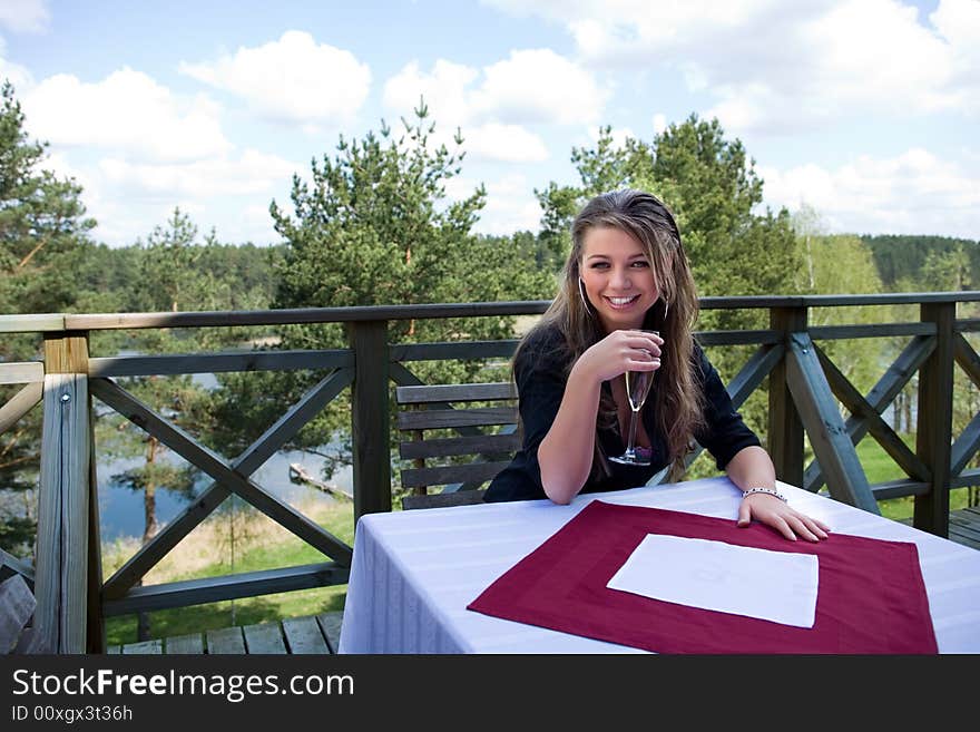 Young girl with glass of champagne on veranda