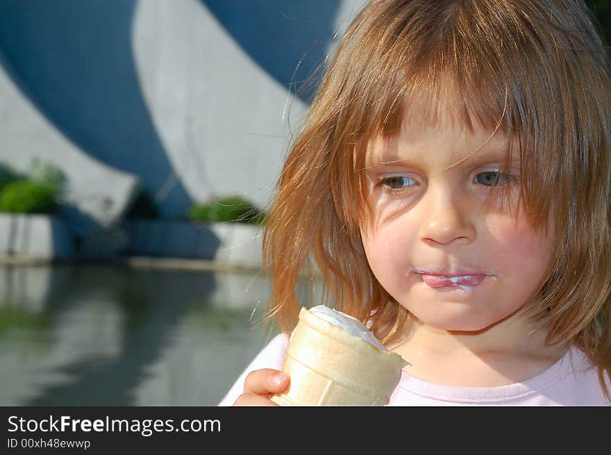Portrait of a little pretty girl eating ice-cream outdoors