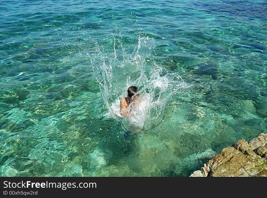 A boy jumping in the limpid sea of Isola d'Elba in Tuscany. A boy jumping in the limpid sea of Isola d'Elba in Tuscany