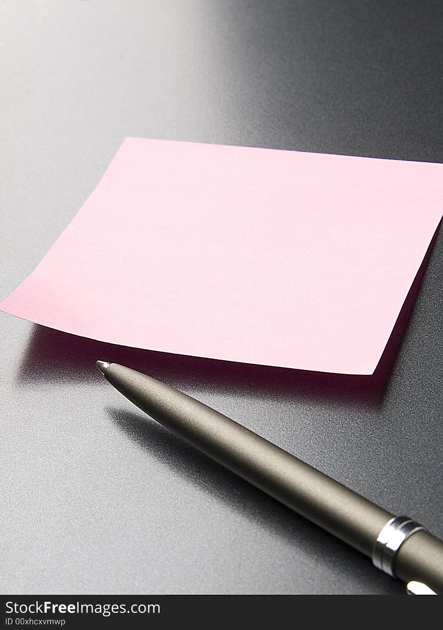 Pen lays near to an orange sticker on a grey background. Pen lays near to an orange sticker on a grey background