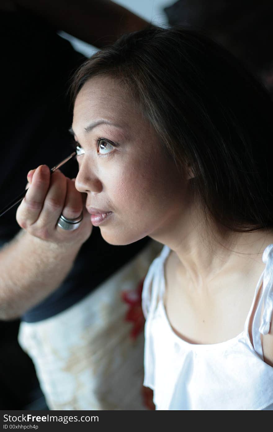 Thai model having her cosmetics done by a make-up artist. Thai model having her cosmetics done by a make-up artist.