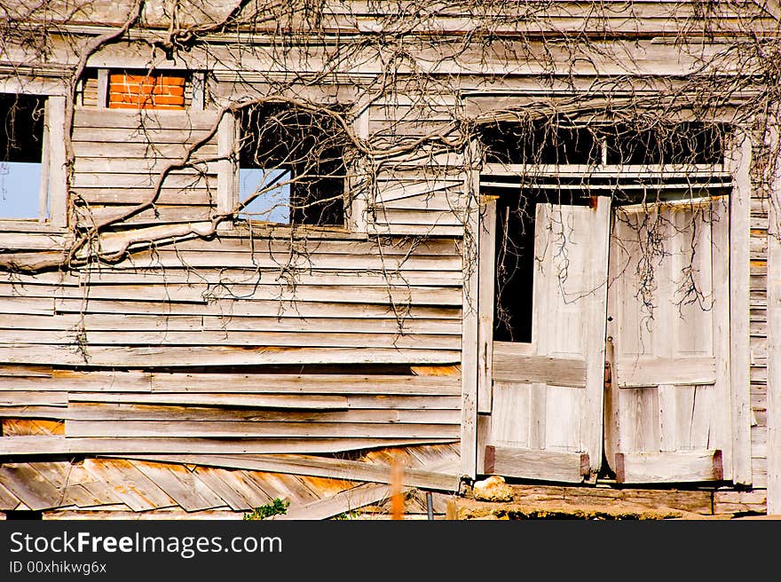 Very old, dilapidated buidling with door and windows,  Building has been covered with vines.  Symbol of decay, neglect or the passage of time etc. Very old, dilapidated buidling with door and windows,  Building has been covered with vines.  Symbol of decay, neglect or the passage of time etc.