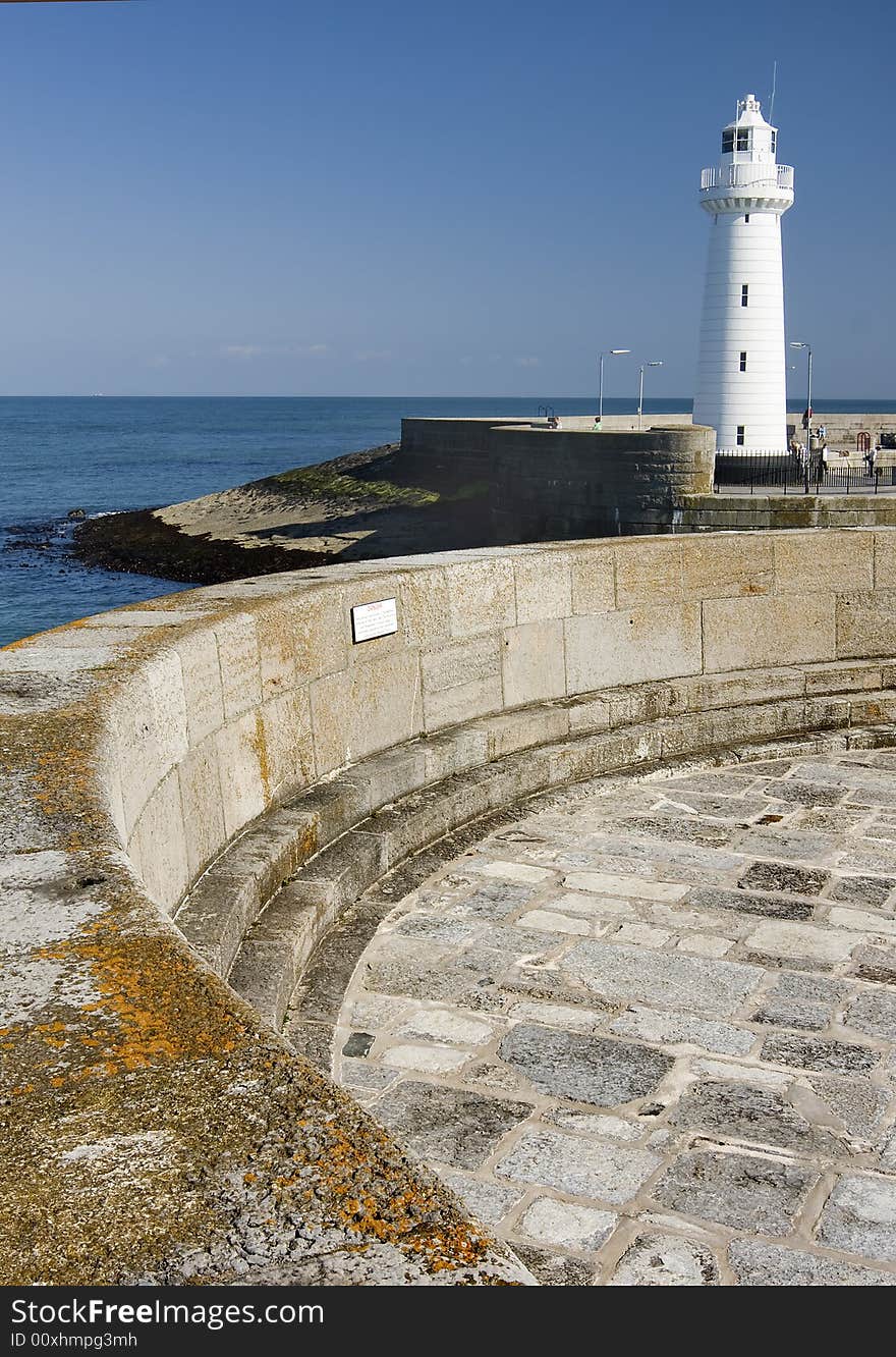 A light house on a harbour with blue sky. A light house on a harbour with blue sky