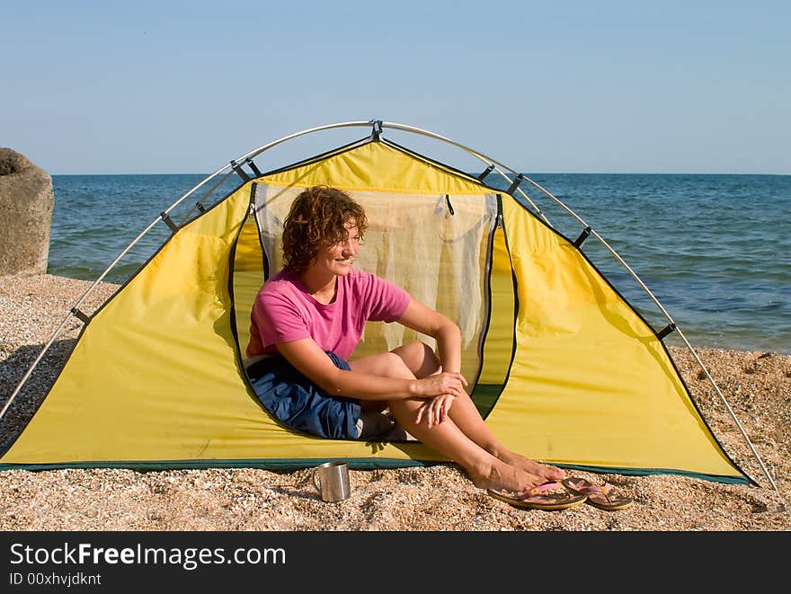 Smyling red-haired woman sitting near of tent at sea coast. Smyling red-haired woman sitting near of tent at sea coast