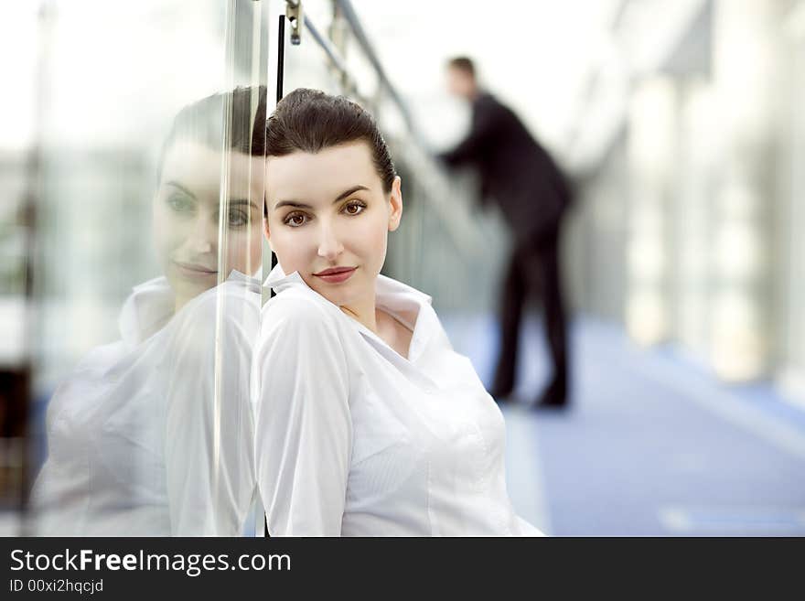 Portrait of young woman sitting on the floor in modern office building corridor and leaning against glass balustrade. Portrait of young woman sitting on the floor in modern office building corridor and leaning against glass balustrade