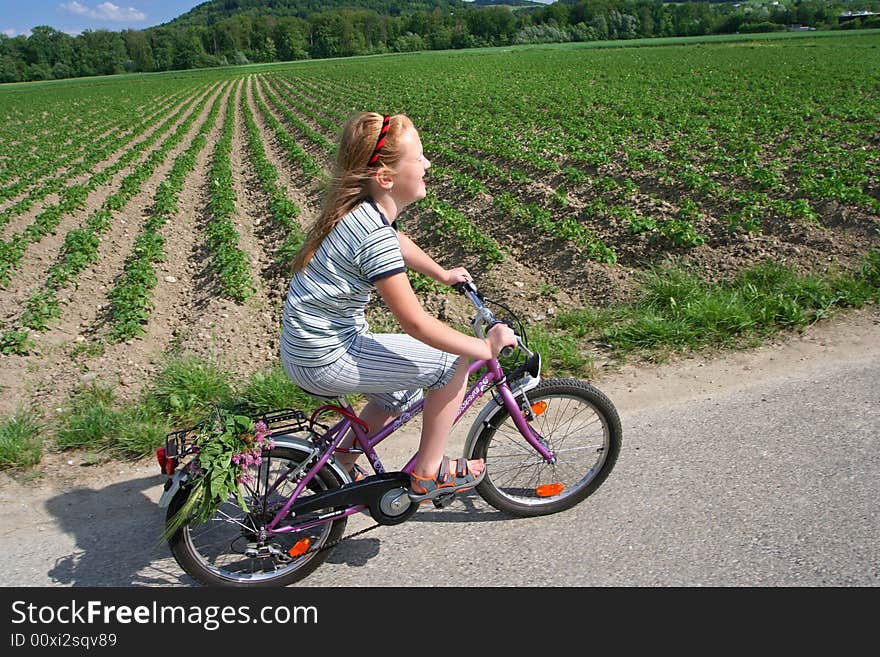 Girl cyclist riding along an asphalt road alow the field. Girl cyclist riding along an asphalt road alow the field