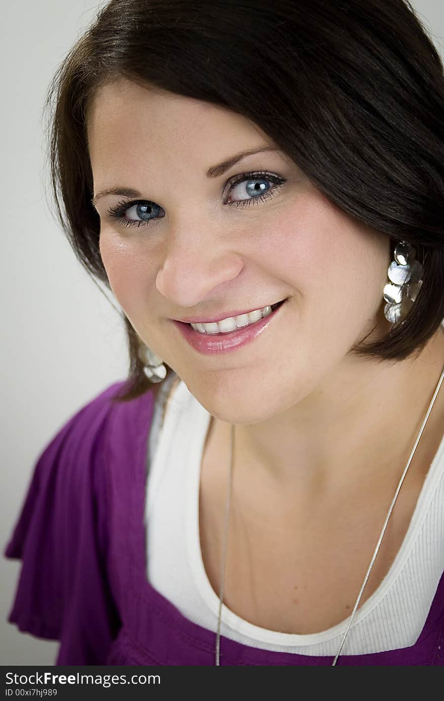 A blue-eyed and brunette Caucasian woman wearing a purple and a white shirt smiling. A blue-eyed and brunette Caucasian woman wearing a purple and a white shirt smiling