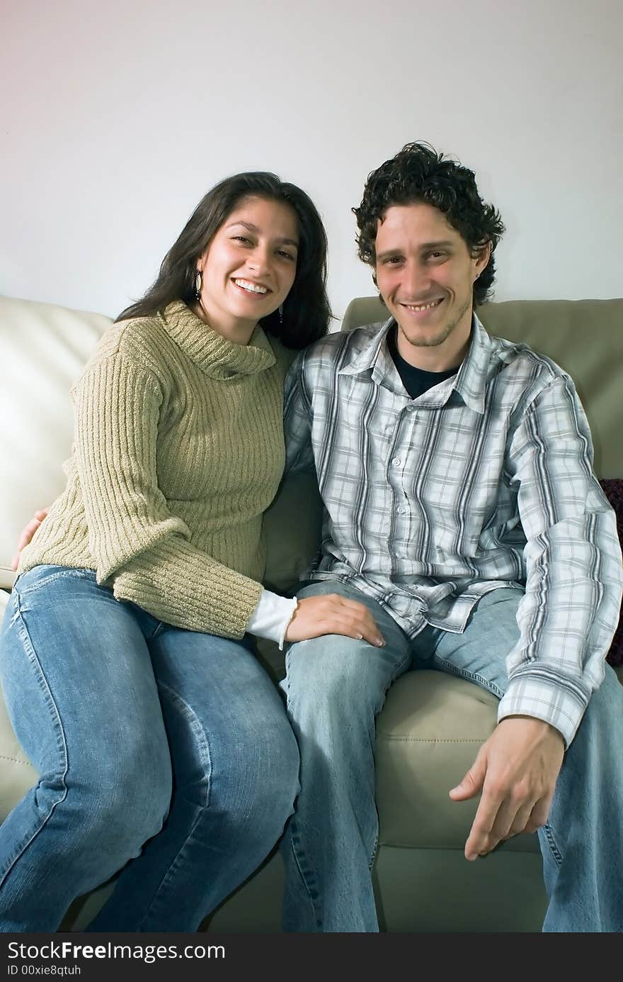 Attractive couple hugging each other and smiling while sitting on their living room couch. Attractive couple hugging each other and smiling while sitting on their living room couch