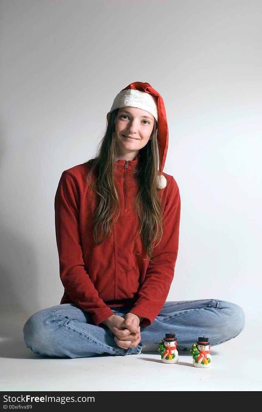 Beautiful young woman in a red jacket, jeans and a santa hat with two snowman ornaments in front of her. Vertically framed shot. Beautiful young woman in a red jacket, jeans and a santa hat with two snowman ornaments in front of her. Vertically framed shot.