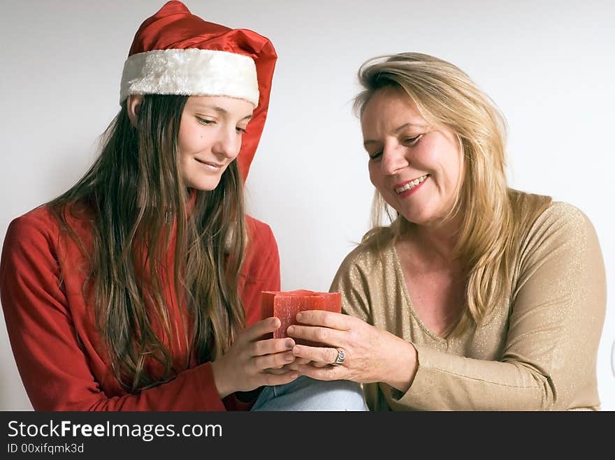 Mature woman and her daughter getting into the christmas spirit and holding a burning christmas candle. Both women are looking at the candle. Mature woman and her daughter getting into the christmas spirit and holding a burning christmas candle. Both women are looking at the candle