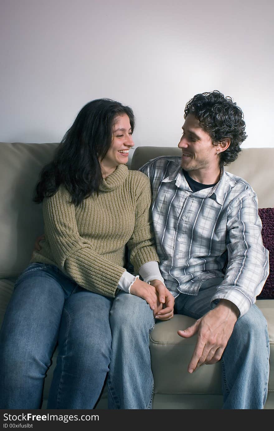 Loving couple sitting on the couch and gazing deeply at each other. Vertically framed shot.