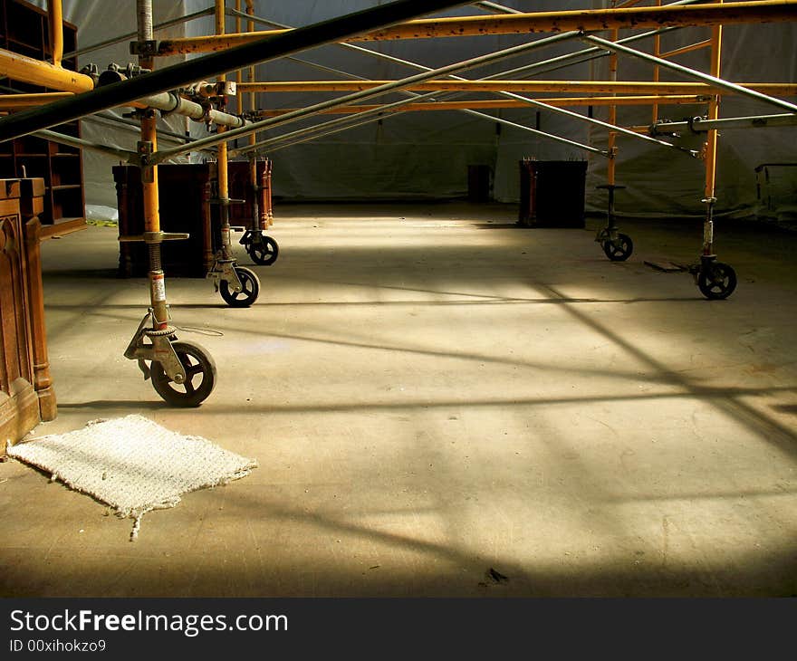 Horizontal shot of a lower half of a scaffolding in a room under construction.  Beautiful yellow sunlight is pouring into the room from above. Horizontal shot of a lower half of a scaffolding in a room under construction.  Beautiful yellow sunlight is pouring into the room from above.