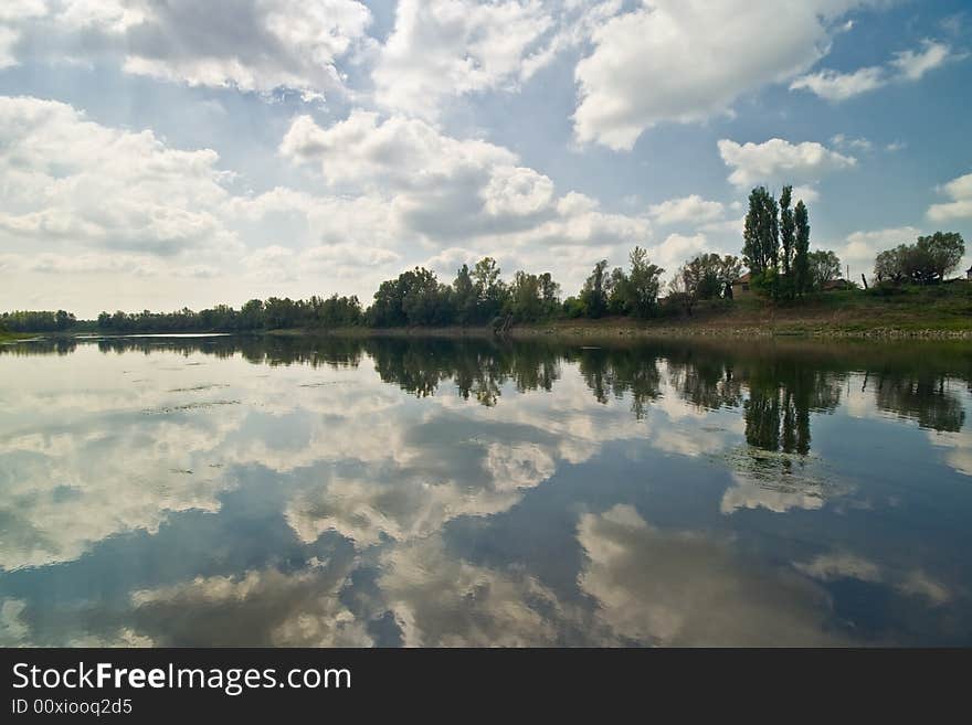 Cloudy sky with forest and reflection in river