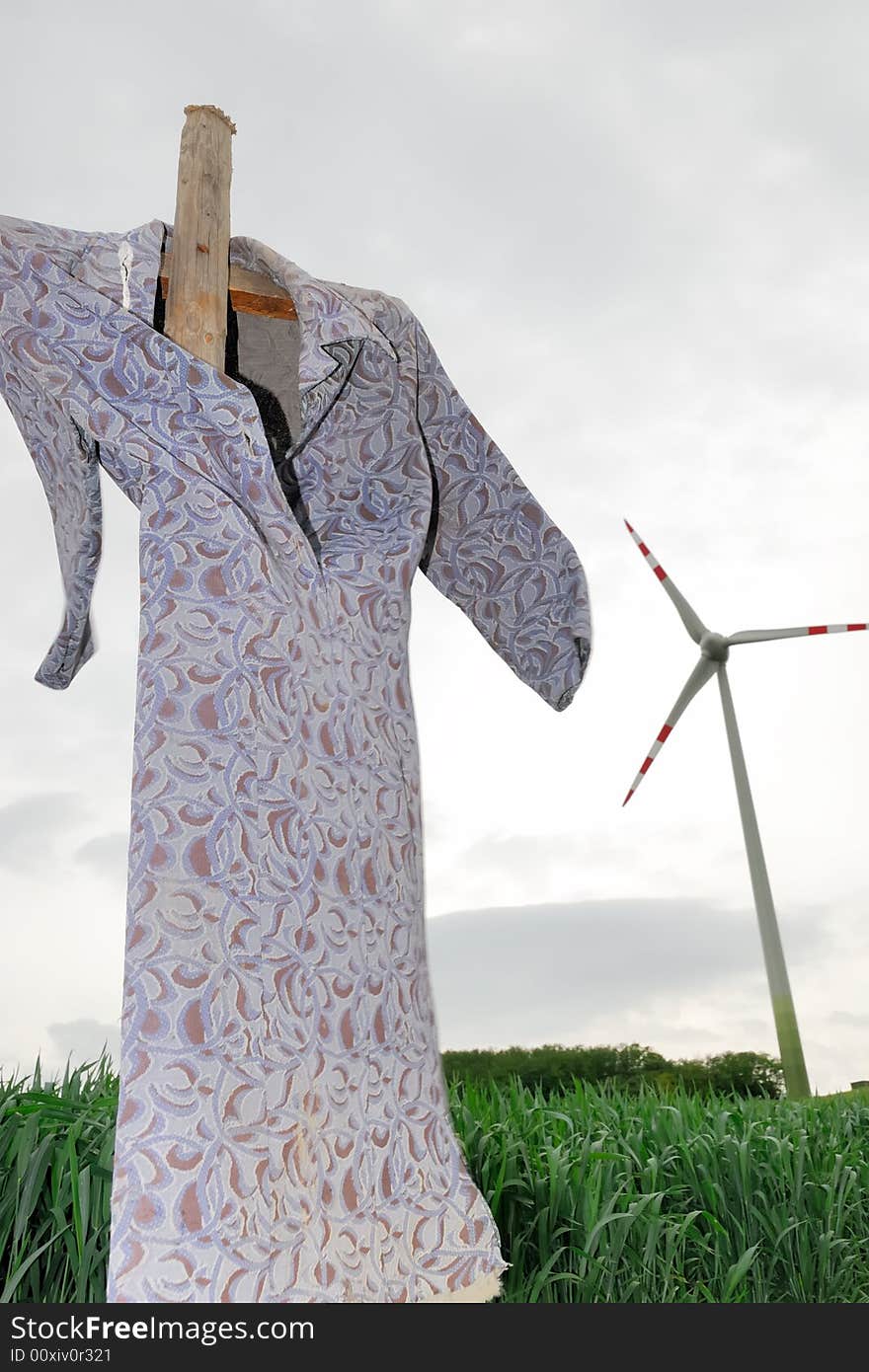 Scarecrow on a corn field with modern windmill. Scarecrow on a corn field with modern windmill