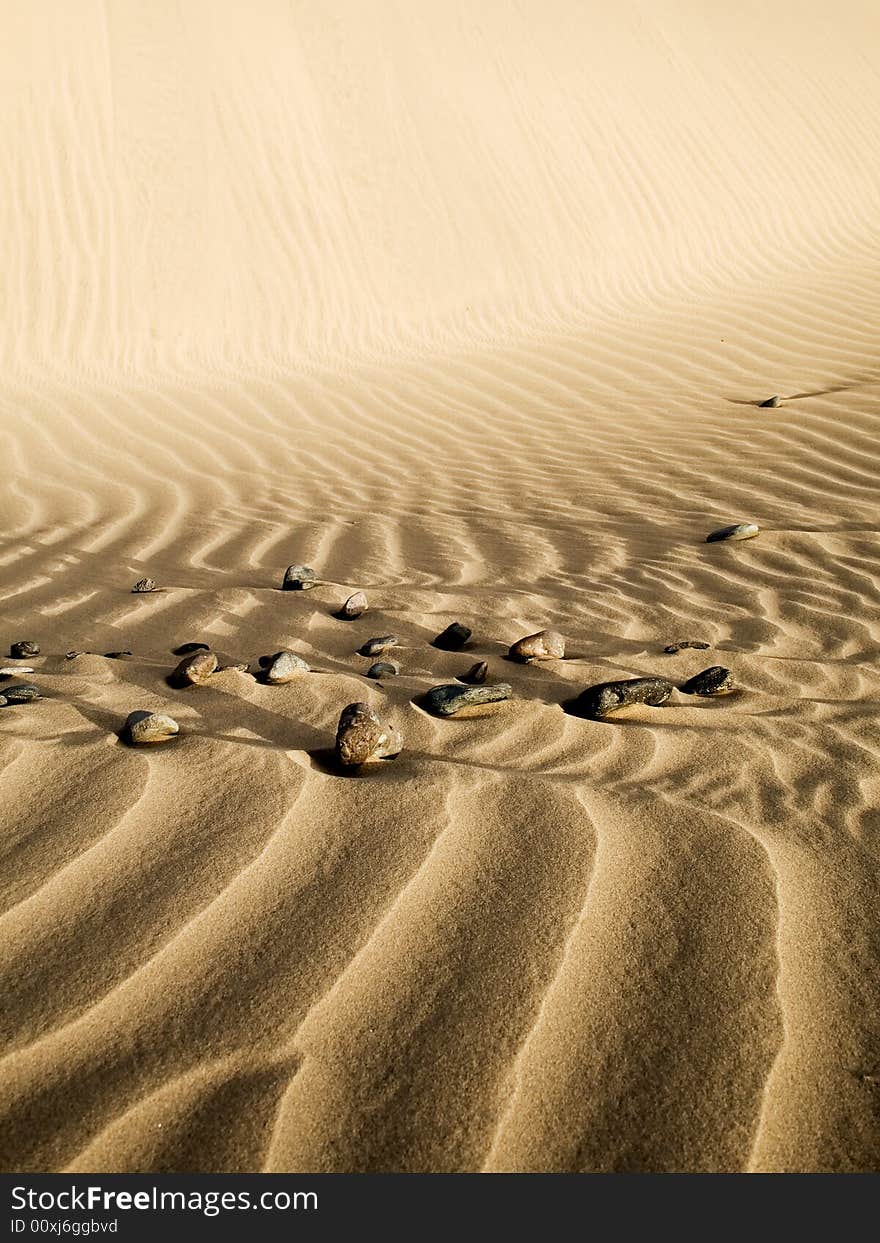 Waves In The Sand With Stones