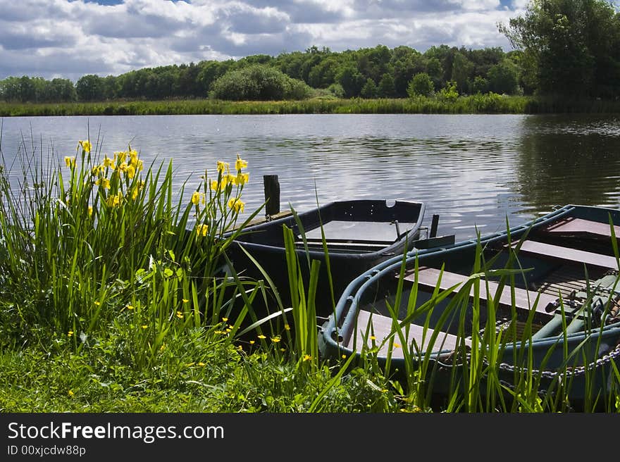 Two old boats at the edge of a lake, with one boat almost sunk