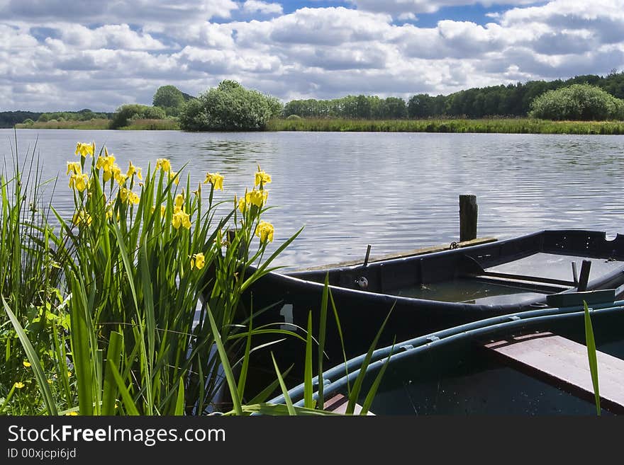 Two old boats at the edge of a lake, with one boat almost sunk. Two old boats at the edge of a lake, with one boat almost sunk