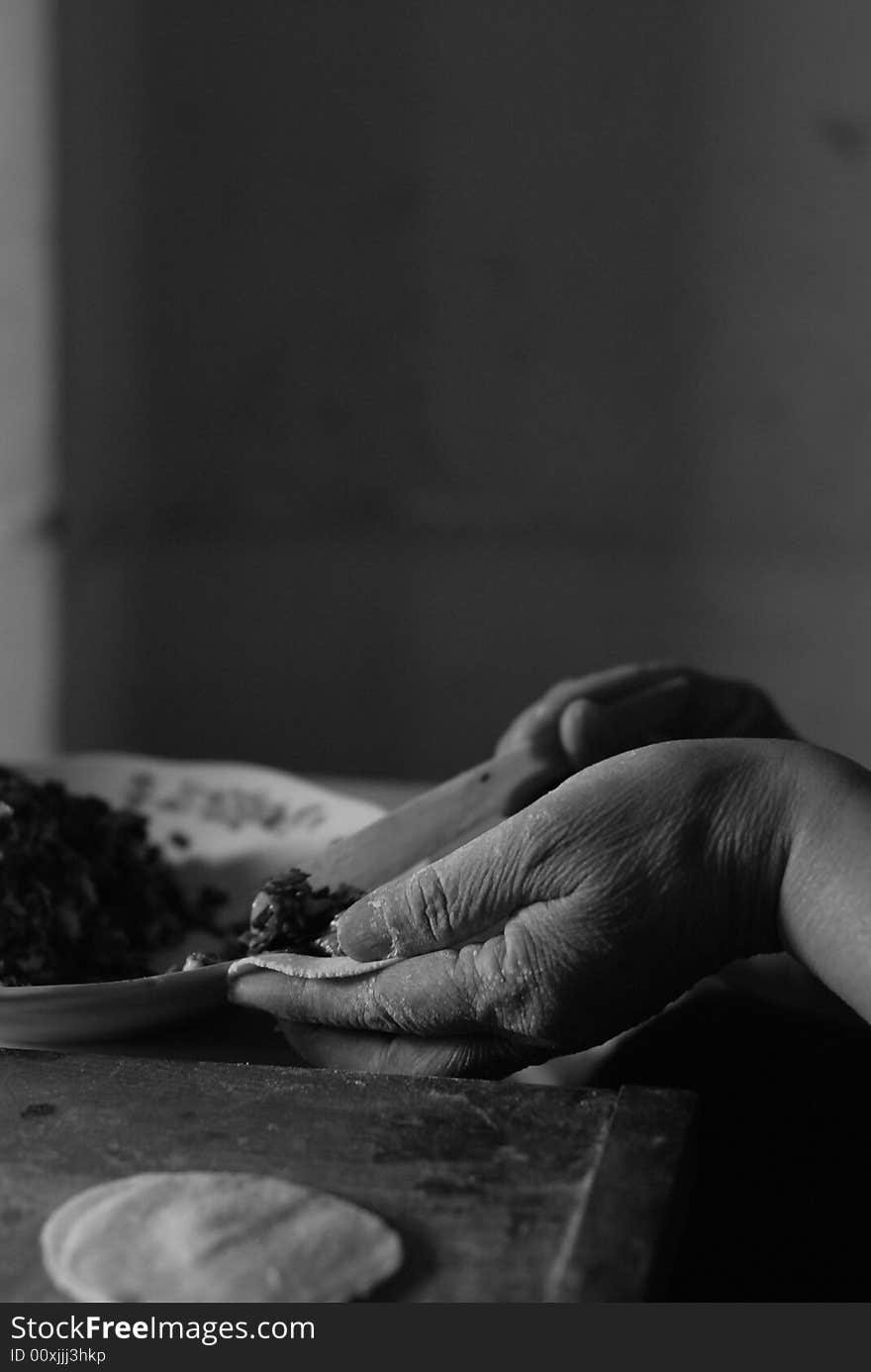 View of elderly person's hands making the pastry for Chinese dumplings. Picture is black and white. View of elderly person's hands making the pastry for Chinese dumplings. Picture is black and white.