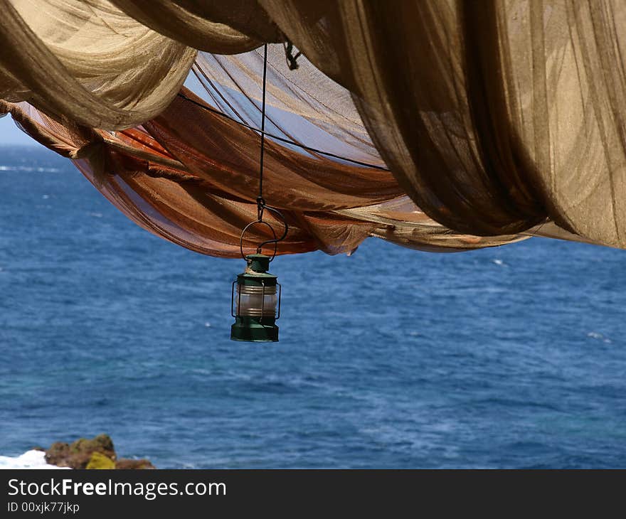 Storm lamp hanging below fishing net canopy. Storm lamp hanging below fishing net canopy