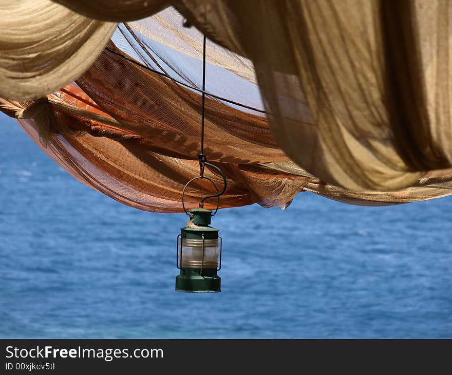 Single gas lamp hanging below fishing net canopy. Single gas lamp hanging below fishing net canopy