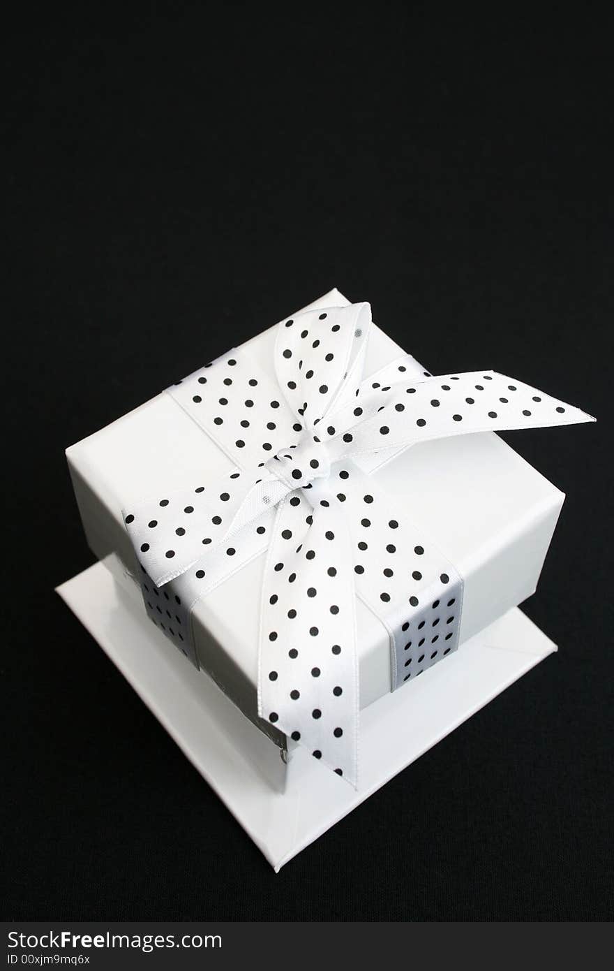 Small white box with a black and white spotted ribbon