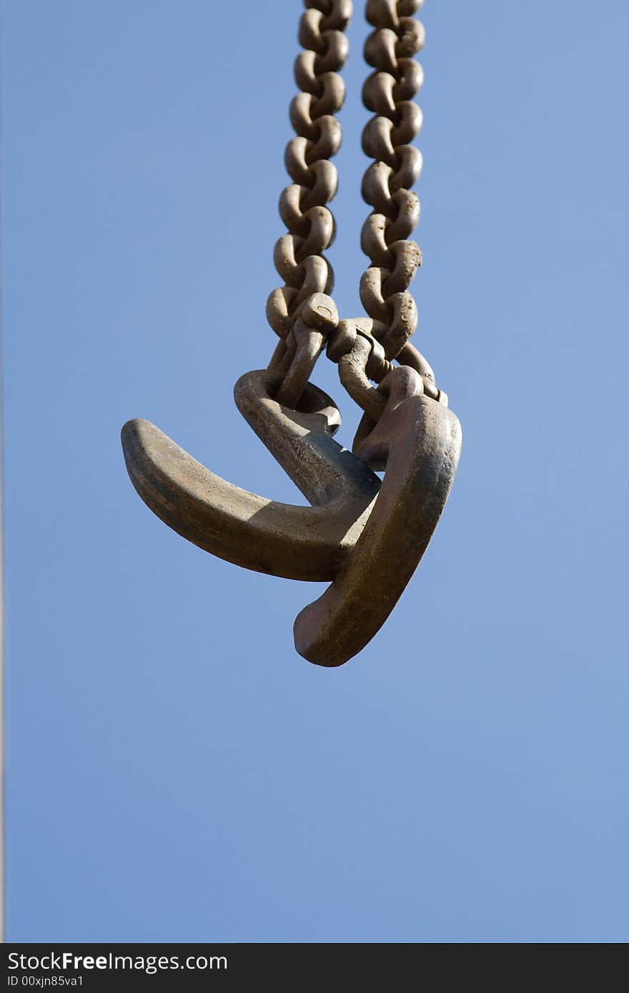 Two crane hooks with sky in the background