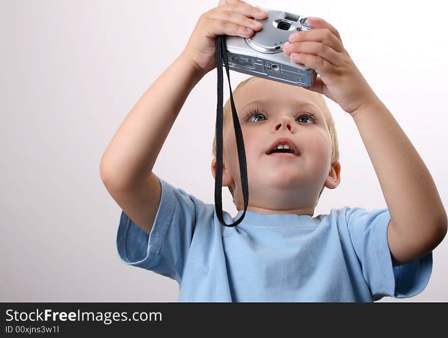 Shy toddler holding a silver camera, looking at his object. Shy toddler holding a silver camera, looking at his object