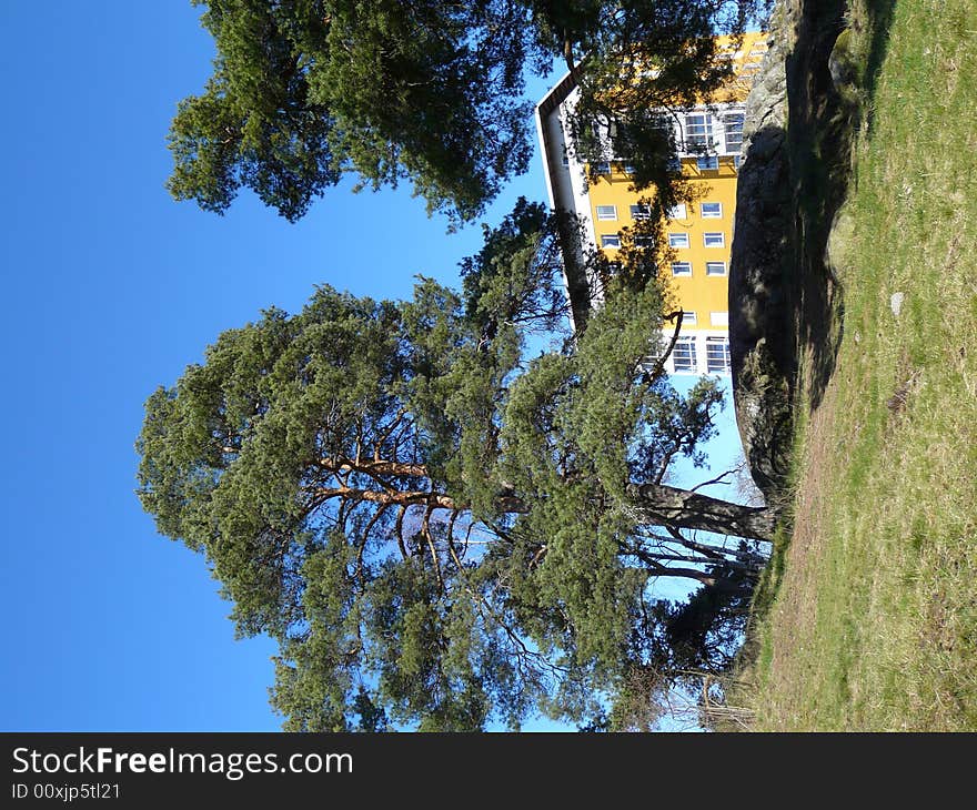 A yellow apartmenthouse behind a hill. A yellow apartmenthouse behind a hill.