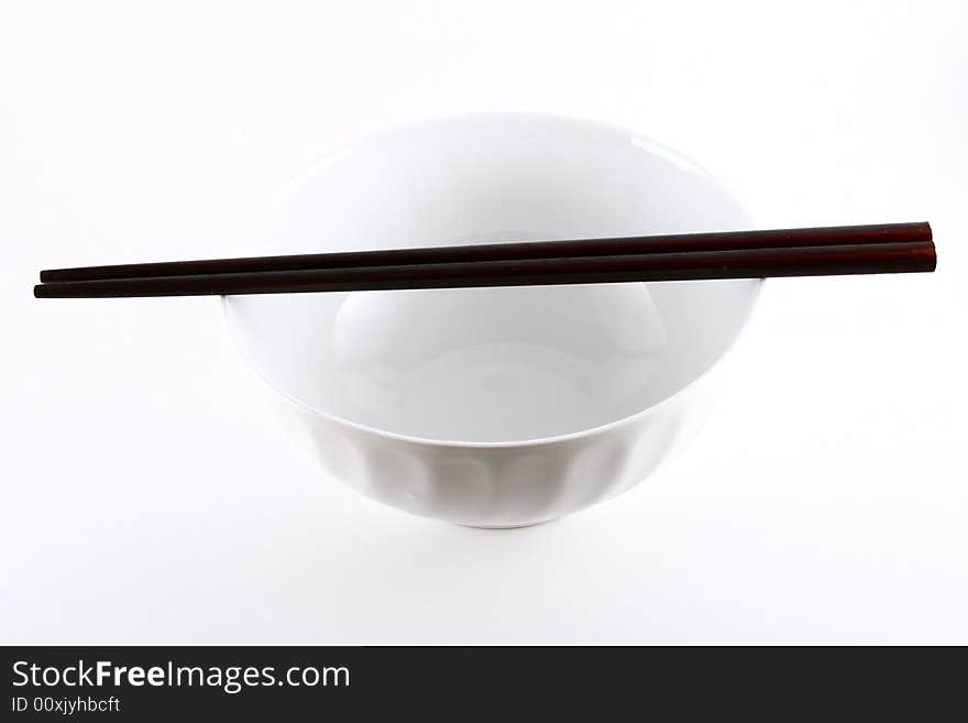 A pair of chopsticks placed on top of a white bowl isolated on white. A pair of chopsticks placed on top of a white bowl isolated on white.