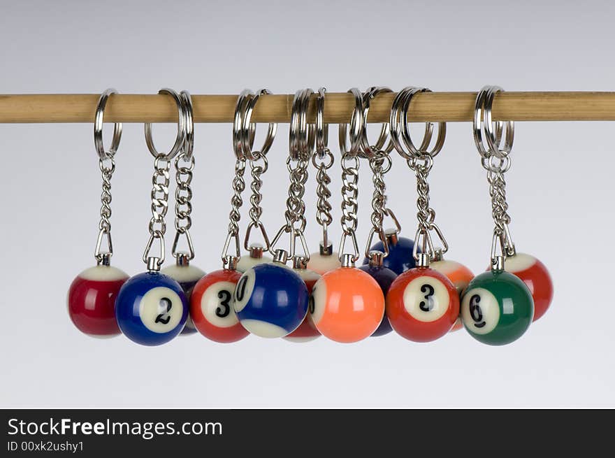 A number of pool balls miniaturized and attached to keyrings and hanging off a stick. A number of pool balls miniaturized and attached to keyrings and hanging off a stick.