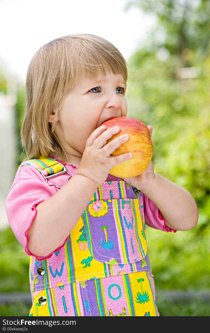 Little girl in a multi-coloured dress with an appl