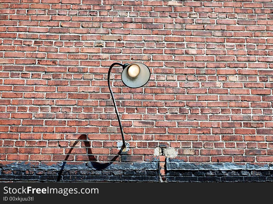 Grunge brick wall with curved lamp fixture turned on. Grunge brick wall with curved lamp fixture turned on